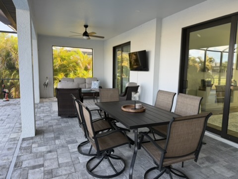 Covered outdoor patio with dining table and ceiling fan TV
