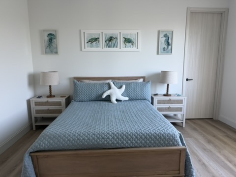 Guest bedroom with coastal art above headboard